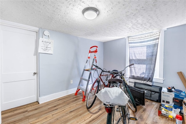 playroom featuring light wood-style floors, baseboards, and a textured ceiling