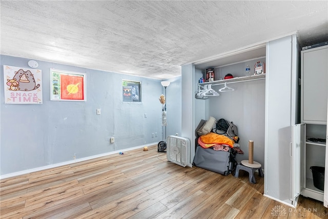 bedroom with a closet, a textured ceiling, baseboards, and hardwood / wood-style flooring