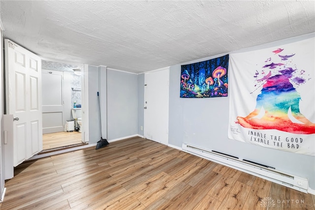 spare room with a textured ceiling, wood finished floors, baseboards, and a baseboard radiator