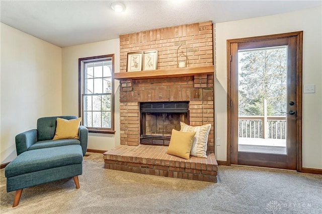 sitting room with baseboards, carpet, and a brick fireplace