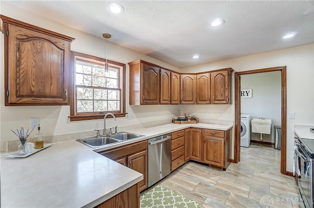 kitchen featuring decorative light fixtures, appliances with stainless steel finishes, washer / clothes dryer, and a sink