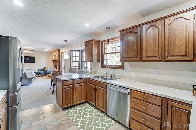 kitchen featuring open floor plan, pendant lighting, light countertops, appliances with stainless steel finishes, and a sink