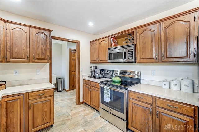 kitchen featuring stainless steel appliances, brown cabinets, and light countertops