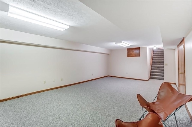 finished below grade area with stairway, carpet flooring, baseboards, and a textured ceiling