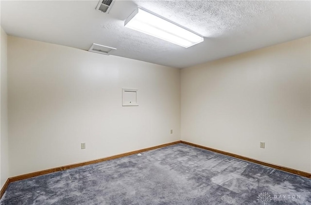 carpeted spare room with visible vents, baseboards, and a textured ceiling