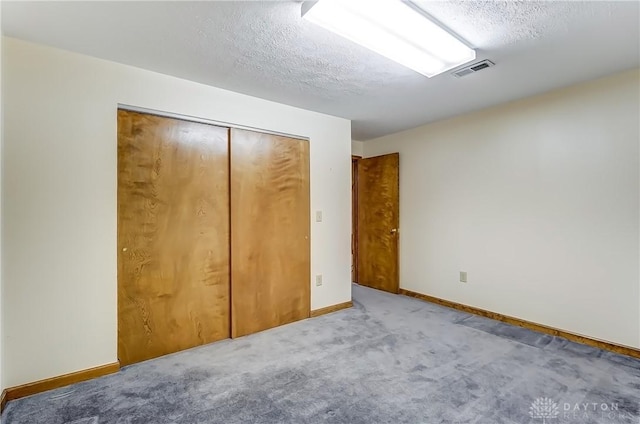 unfurnished bedroom with baseboards, visible vents, carpet floors, a closet, and a textured ceiling