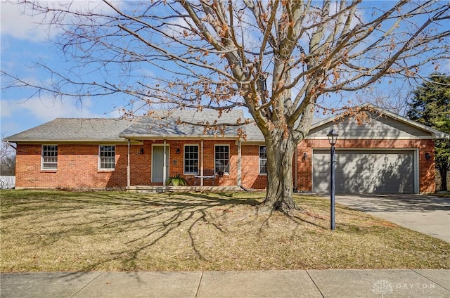 single story home with a porch, an attached garage, concrete driveway, a front lawn, and brick siding