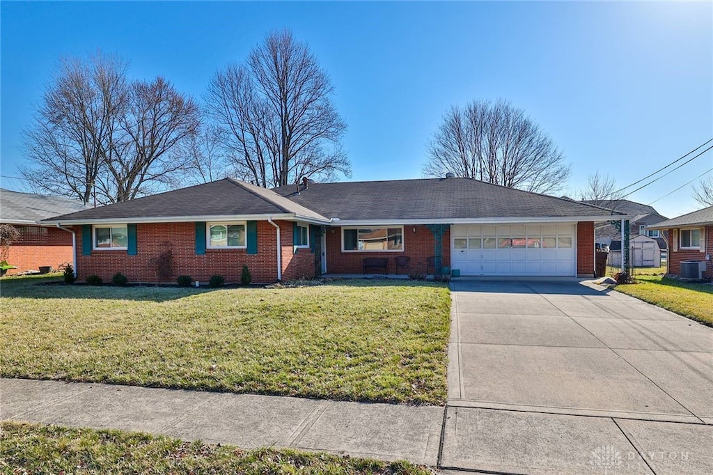 single story home with a garage, a front lawn, central AC unit, and driveway