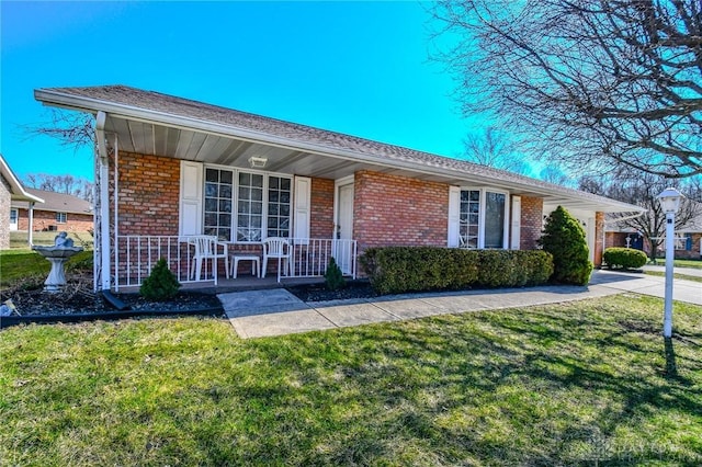 single story home featuring brick siding, a porch, and a front yard