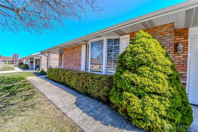 view of side of property with a yard and brick siding