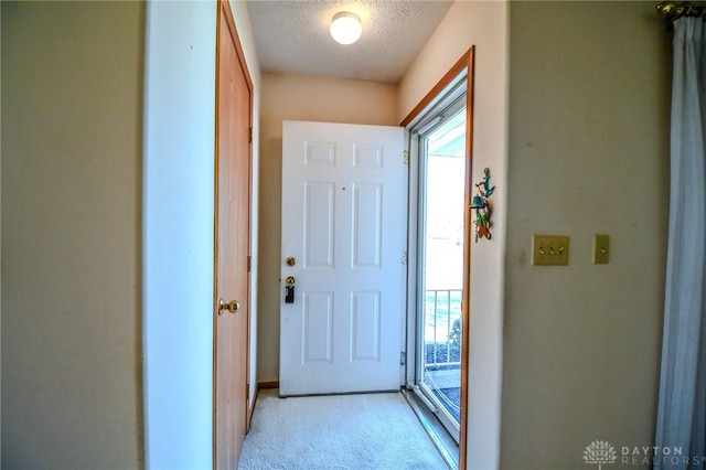 doorway to outside with light carpet and a textured ceiling