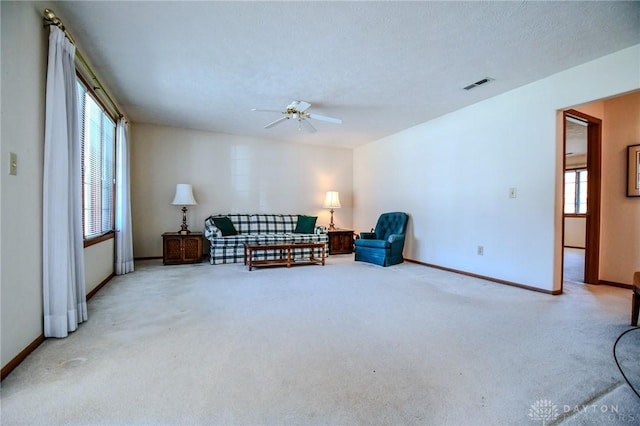 sitting room featuring visible vents, a textured ceiling, carpet floors, baseboards, and ceiling fan