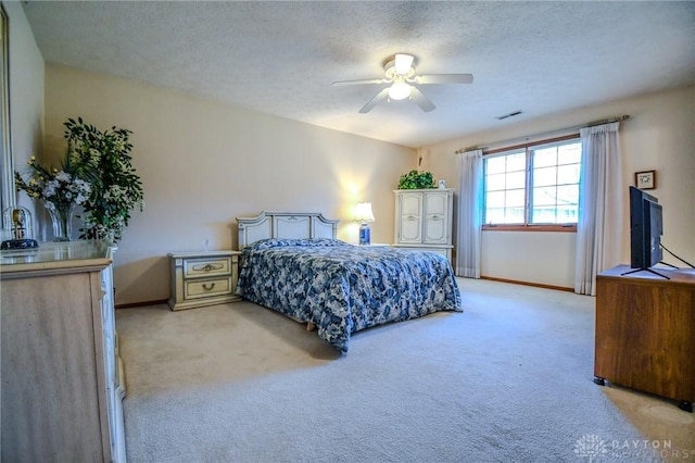 bedroom featuring a textured ceiling, baseboards, visible vents, and light carpet