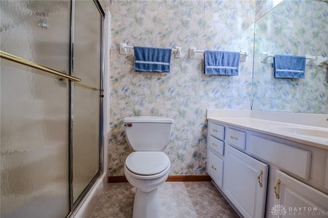 bathroom featuring a shower with door, wallpapered walls, baseboards, toilet, and vanity