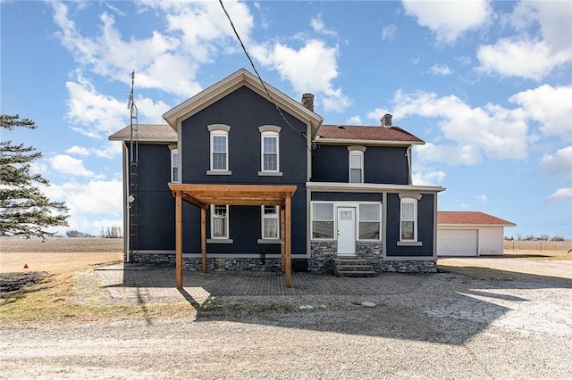 view of front of house with entry steps, stucco siding, an outdoor structure, and a chimney