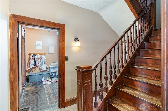 stairway featuring lofted ceiling and visible vents