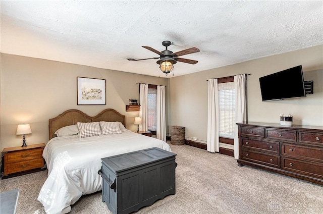 bedroom featuring ceiling fan, light colored carpet, baseboards, and a textured ceiling