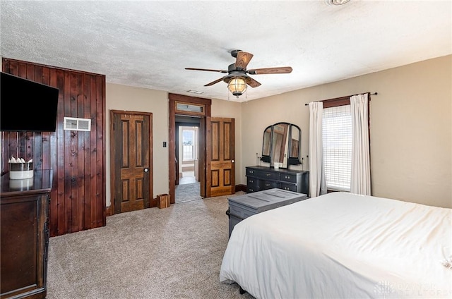 bedroom with a textured ceiling, ceiling fan, visible vents, and light carpet