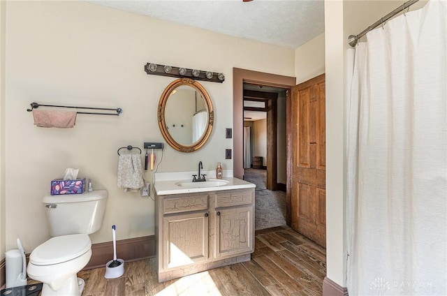 full bath featuring vanity, toilet, wood finished floors, and a textured ceiling