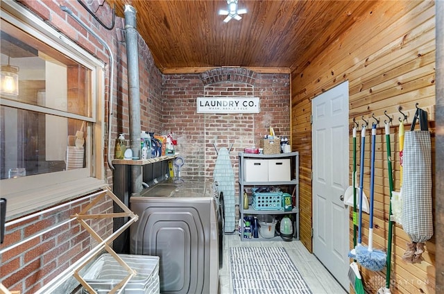 washroom with wood ceiling, brick wall, laundry area, and washing machine and clothes dryer