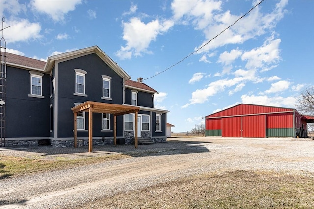 back of house with an outbuilding, an outdoor structure, and stucco siding