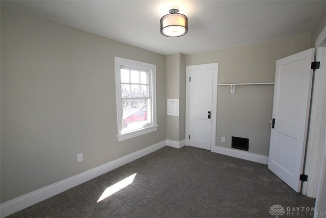 unfurnished bedroom featuring a closet, baseboards, and dark colored carpet