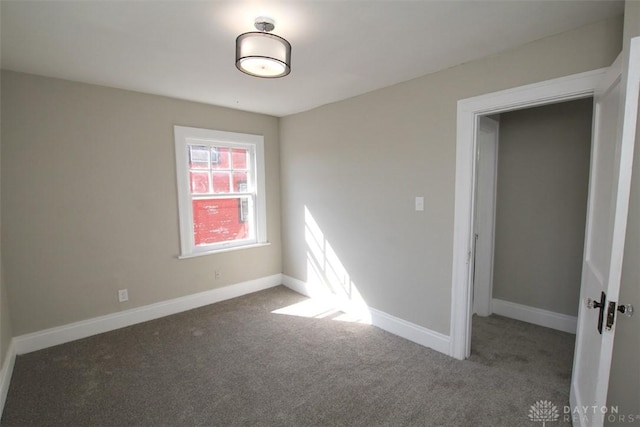 carpeted empty room featuring baseboards