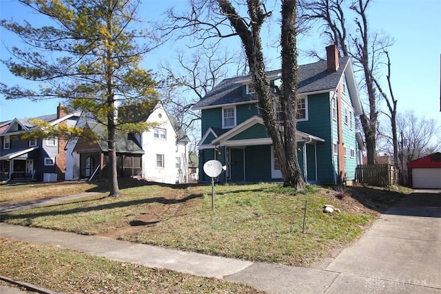 view of front of home with a residential view, a chimney, a detached garage, and a front lawn