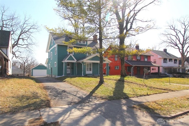 view of front of house featuring a residential view, a front yard, a garage, an outbuilding, and driveway