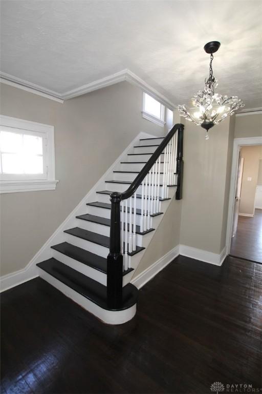 stairs featuring crown molding, baseboards, and wood finished floors