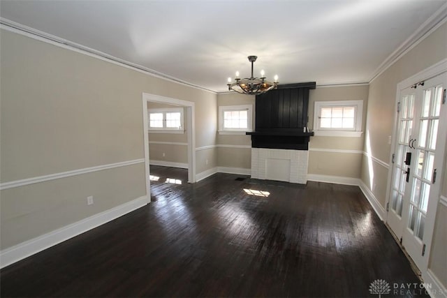 unfurnished living room with dark wood finished floors, a healthy amount of sunlight, baseboards, and an inviting chandelier