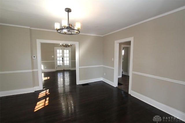 empty room with a notable chandelier, crown molding, dark wood-type flooring, and baseboards