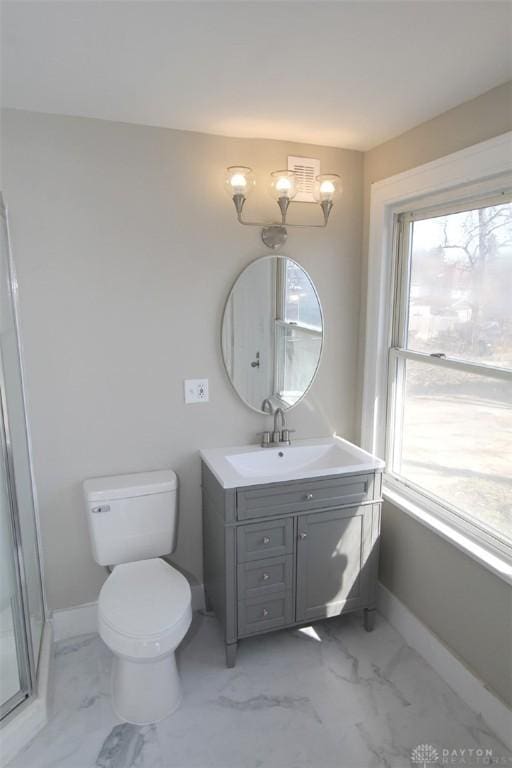 bathroom featuring a healthy amount of sunlight, vanity, marble finish floor, and baseboards