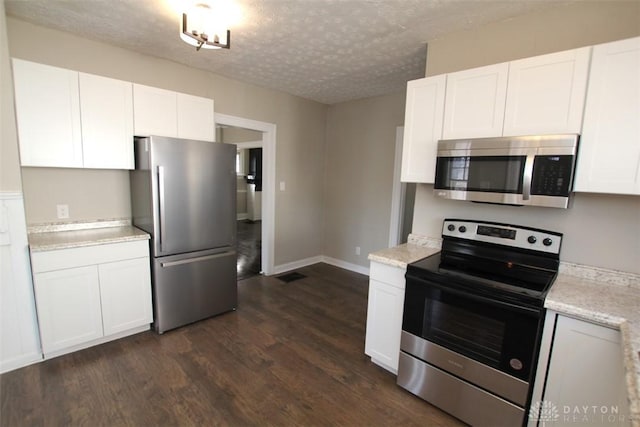 kitchen featuring visible vents, dark wood-type flooring, stainless steel appliances, a textured ceiling, and white cabinetry