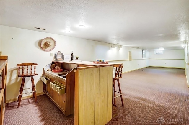 bar featuring visible vents, baseboards, carpet floors, and a textured ceiling