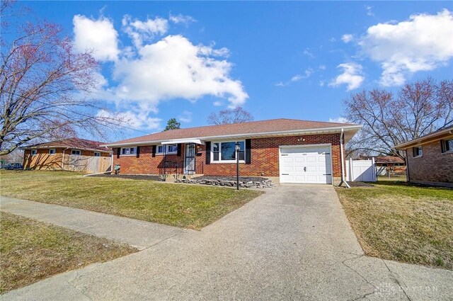 ranch-style house with a front lawn, a gate, fence, concrete driveway, and brick siding