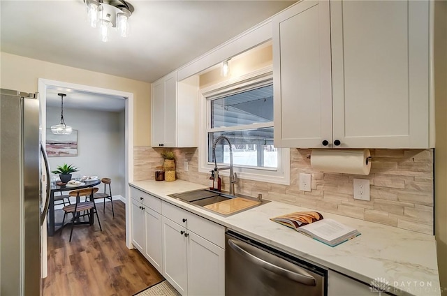 kitchen with tasteful backsplash, dark wood finished floors, stainless steel appliances, white cabinetry, and a sink