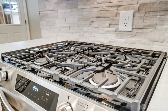 interior details featuring backsplash and stainless steel range with gas cooktop