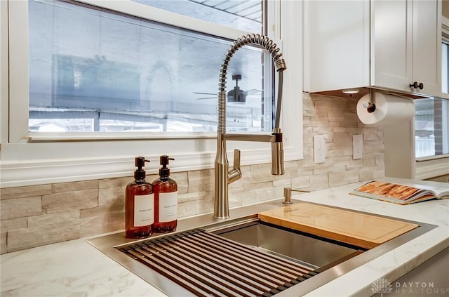 details featuring decorative backsplash, light countertops, white cabinets, and a sink