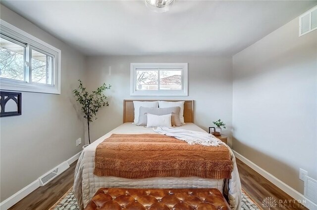 bedroom featuring visible vents, multiple windows, and wood finished floors