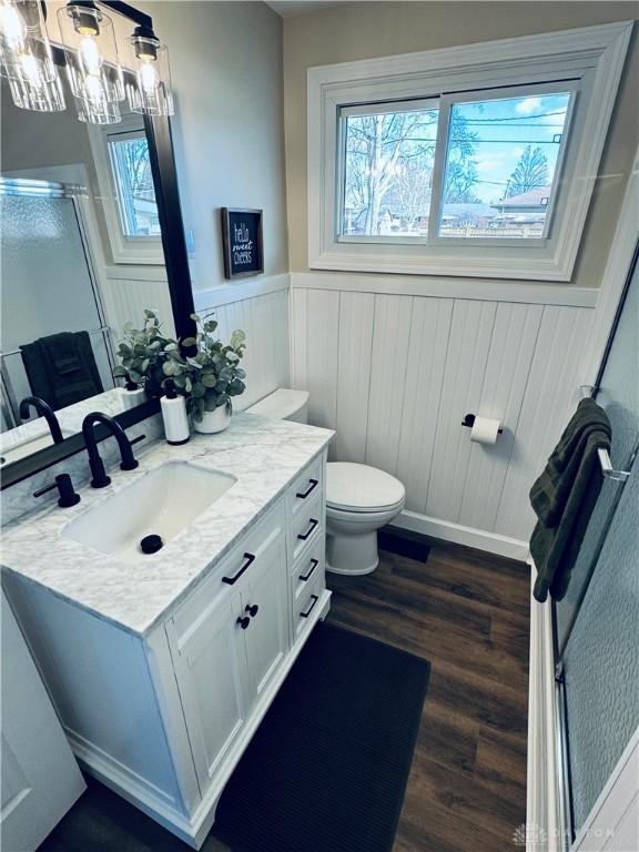 full bath featuring a wainscoted wall, toilet, a stall shower, wood finished floors, and vanity