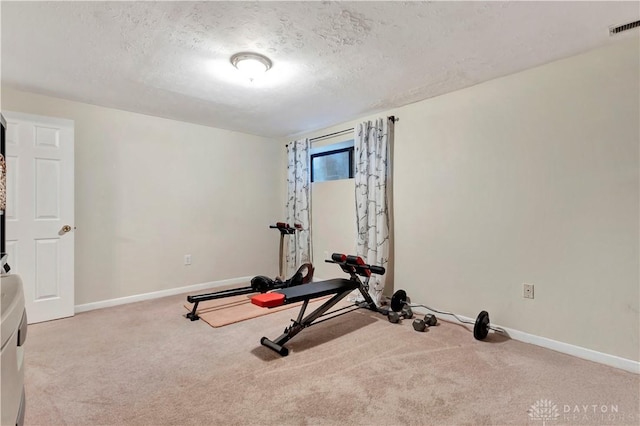 exercise room with carpet flooring, baseboards, visible vents, and a textured ceiling