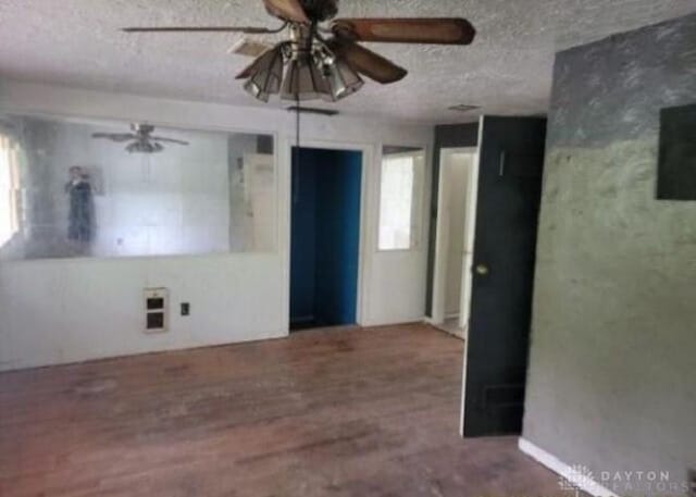 empty room featuring wood finished floors, a ceiling fan, and a textured ceiling