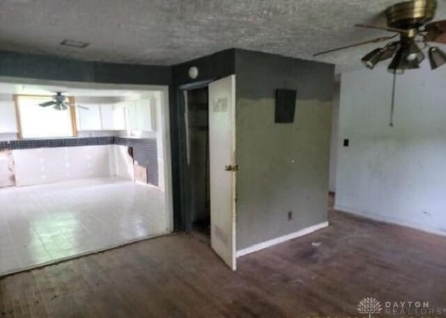 interior space with a textured ceiling, a ceiling fan, and wood finished floors