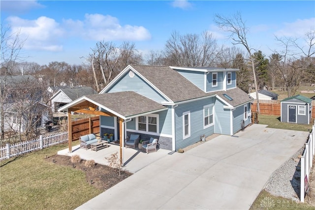 view of front facade featuring an outdoor living space, fence private yard, a patio, and roof with shingles