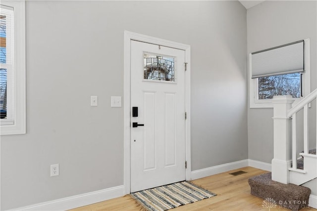 entryway with stairs, wood finished floors, and baseboards