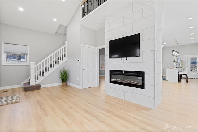 living area with stairway, wood finished floors, baseboards, and a tile fireplace