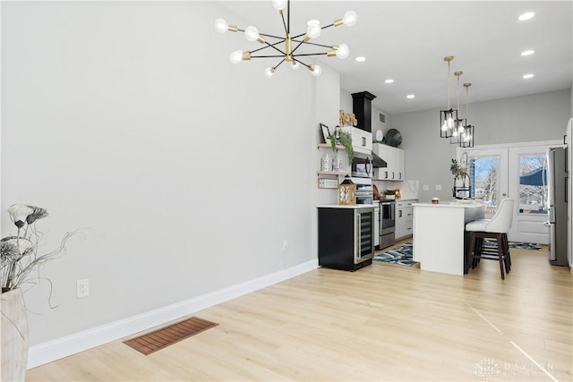 kitchen featuring visible vents, light countertops, appliances with stainless steel finishes, a kitchen breakfast bar, and a chandelier