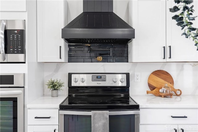 kitchen with backsplash, white cabinetry, stainless steel appliances, and wall chimney range hood