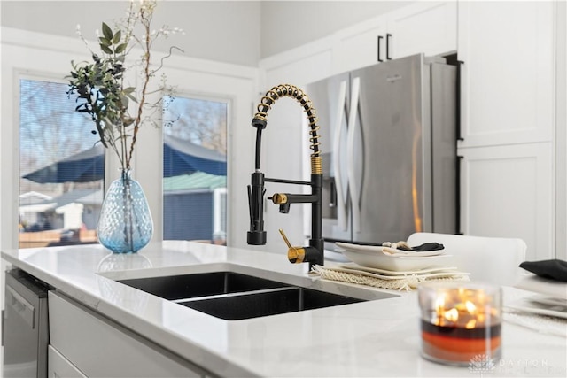 kitchen with a healthy amount of sunlight, white cabinetry, light countertops, and a sink